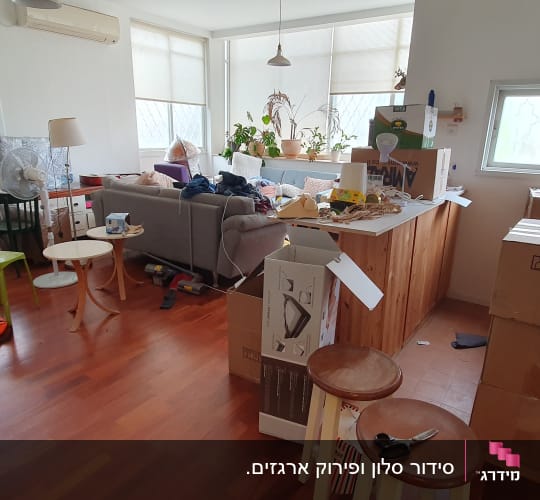 חדר עם קופסאות קרטון, רהיטים וכלי בית מפוזרים